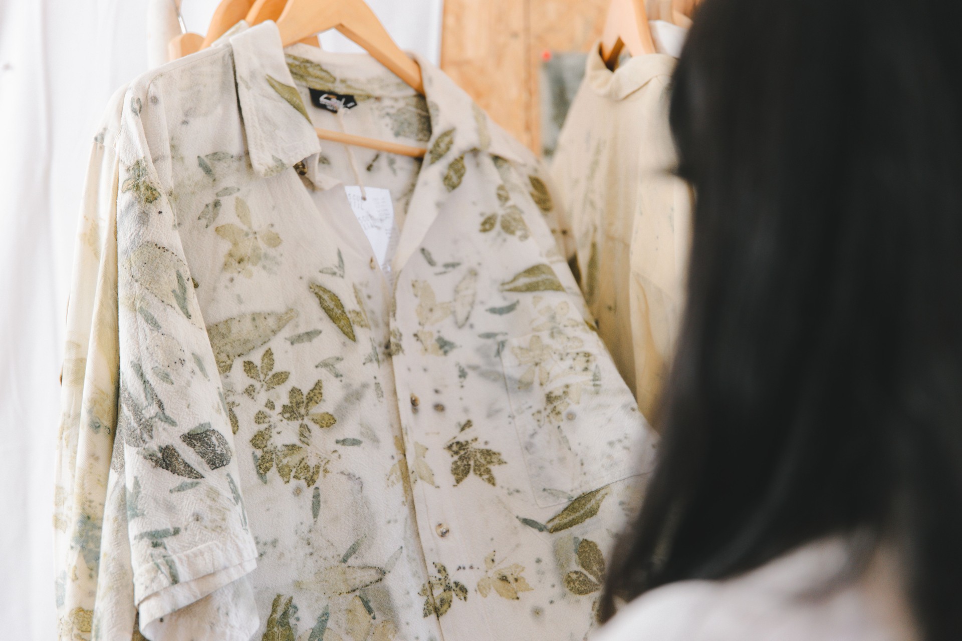 Textile artist holding a shirt with natural flowers dye on it. Botanical eco-friendly print on fiber clothing wardrobe.